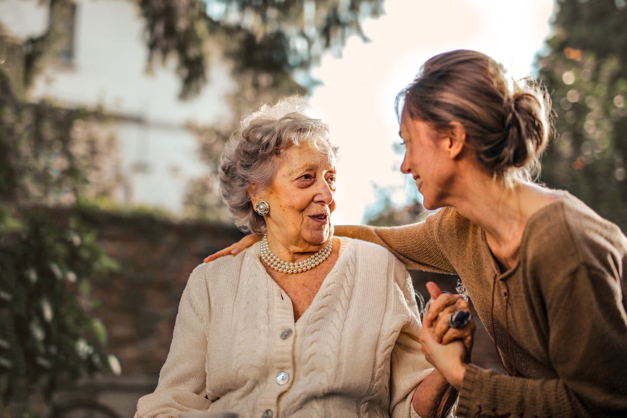 Joyful adult daughter with her senior mother in a garden
